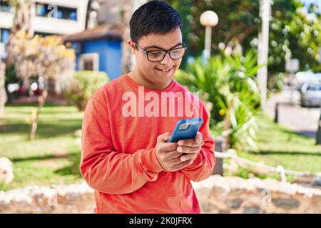 Down syndrome man smiling confident using smartphone at park Stock Photo