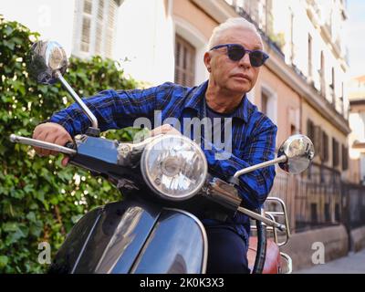 Low angle of smiling woman in vintage outfit sitting on retro motorbike and cheerfully looking away Stock Photo