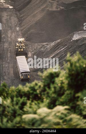 Aerial view of modern loader transporting cargo along coal mining stock in daylight Stock Photo