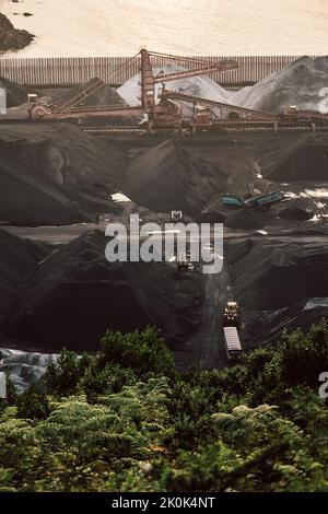 Aerial view of modern loader transporting cargo along coal mining stock in daylight Stock Photo