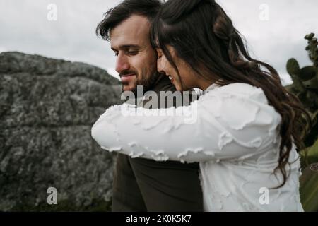 Loving bride and groom in stylish clothes hugging in nature on wedding day Stock Photo