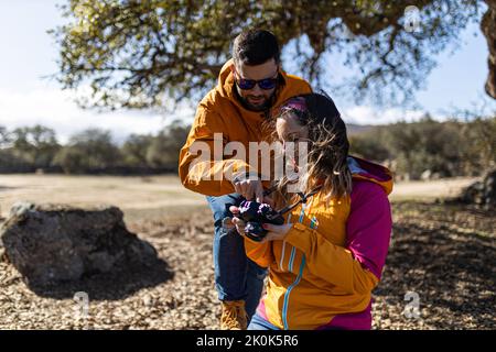 Young woman and boyfriend taking picture of nature landscape with professional camera while hiking outdoors Stock Photo