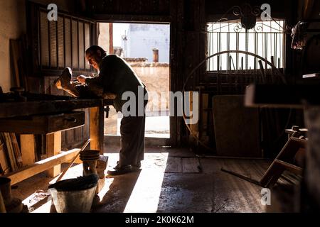Senior woodworker in glasses working with piece of lumber in workshop Stock Photo