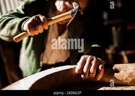 Senior carpenter using manual tool while working with piece of lumber in dark workshop Stock Photo
