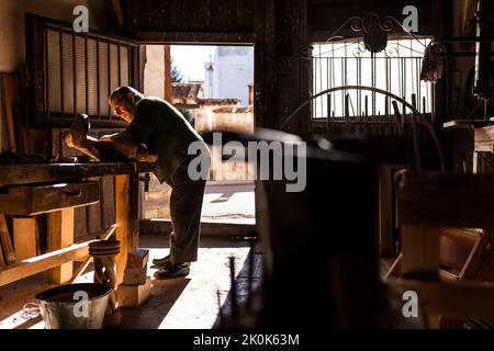 Senior woodworker in glasses working with piece of lumber in workshop Stock Photo