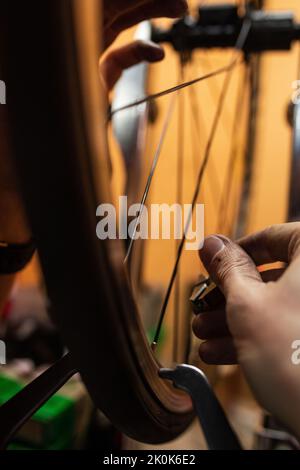 Unrecognizable technician using tool to fix wheel of broken bicycle while working in garage Stock Photo