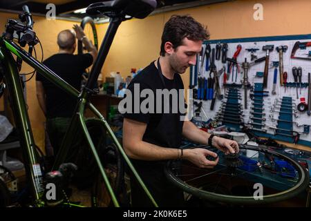 Technician with dirty hands fixing bicycle wheel while working in workshop Stock Photo