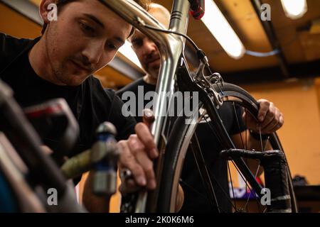 Technician with dirty hands fixing bicycle wheel while working in workshop Stock Photo