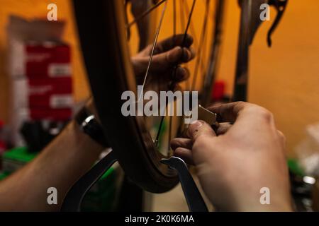 Technician with dirty hands fixing bicycle wheel while working in workshop Stock Photo