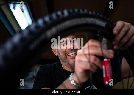 Technician with dirty hands fixing bicycle wheel while working in workshop Stock Photo