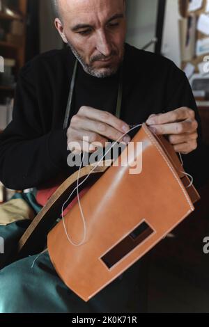 Crop tailor in dickey sewing by needle leather textile on workplace Stock Photo
