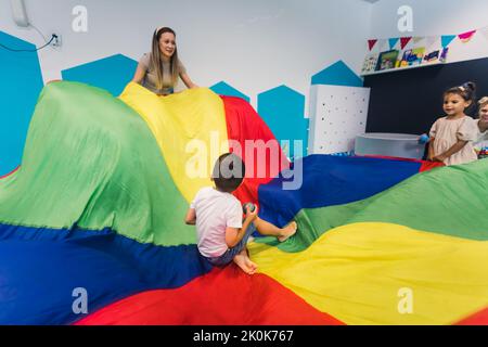 Happy toddlers having an active sensory play with texture and colors at the nursery school. Kids wellness. Early fine motor and gross motor skills development. High quality photo Stock Photo