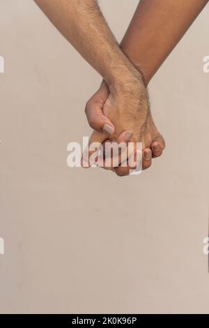 Unrecognizable couple holding hands on chest of man in white t shirt during romantic date Stock Photo