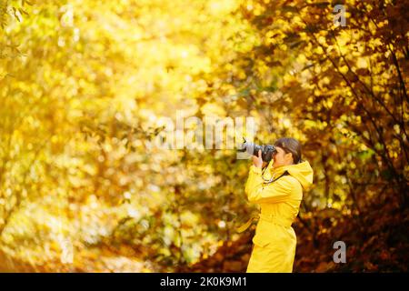 Young Pretty Caucasian Happy Smiling Girl Woman On Road In Autumn Forest. Tourist Woman Walking And Taking Photos In Forest. Lady Photographed Nature Stock Photo