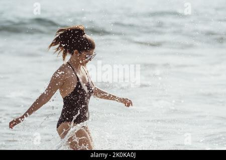 Young woman splashing water in summertime at the beach Stock Photo