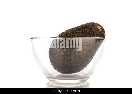 One ripe organic avocado in a glass bowl, close-up, isolated on a white background. Stock Photo