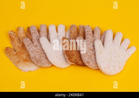 Hands made from toasted sliced bread. Multicultural hands concept together on a yellow background Stock Photo