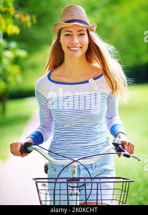 Out for a refreshing ride in the countryside. Portrait of a young woman cycling in the park. Stock Photo