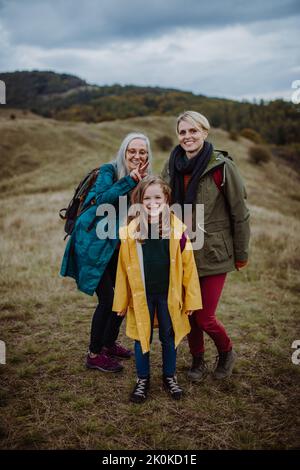 Small girl with mother and grandmother standing and lookiong at view on top of mountain. Stock Photo