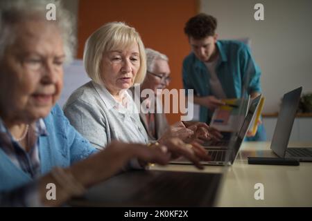 Senior group with young instructor learning together in computer class. Stock Photo