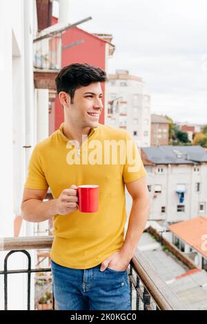 Attractive caucasian man with a coffee cup on the balcony at home looking away Stock Photo