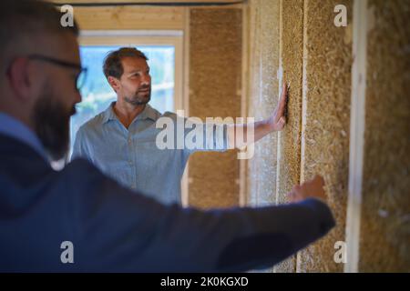 Developer showing unfinished wooden house customer, diy eco-friendly homes concept. Stock Photo