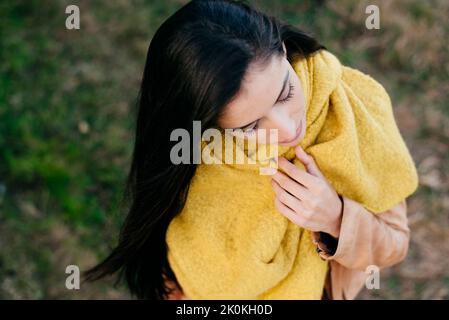 From above portrait of dreamy stylish woman with yellow outfit standing on grass with closed eyes Stock Photo