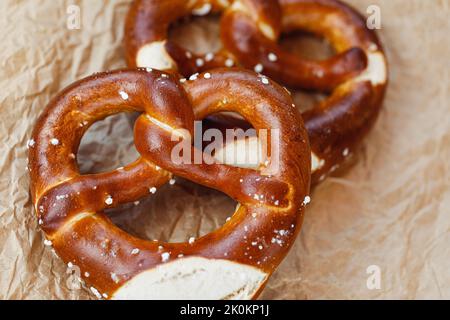 Two homemade freshly baked soft pretzels on brown paper. Traditional Bavarian pretzel for Octoberfest. Close-up Stock Photo