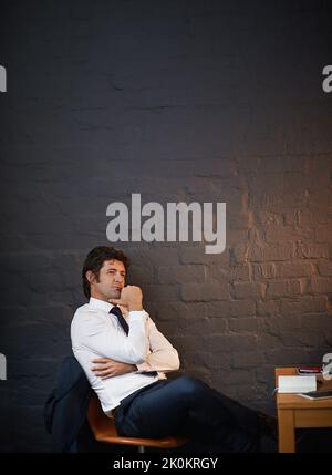Thinking about business. a businessman looking thoughtful while sitting in his office late at night. Stock Photo