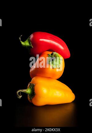 Sweet peppers stacked on black background Stock Photo