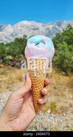 Melting gelato ice cream cone held up to the hot summer day. Stock Photo