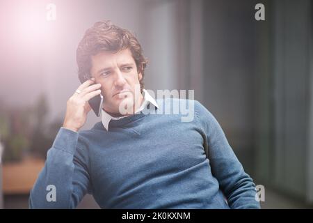 Paying close attention to the needs of his client. a businessman using a phone in the office. Stock Photo