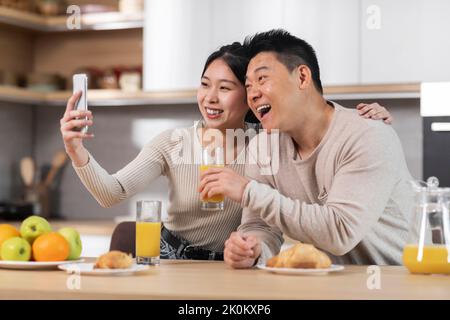 Cute asian couple taking selfie while having breakfast Stock Photo