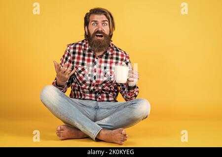 surprised handsome bearded guy with unshaven face and stylish hairdo wear casual clothes drink coffee, surprise Stock Photo