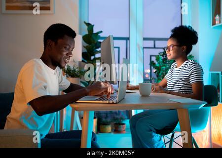 African American couple works together on computer and laptop typing information about project Stock Photo