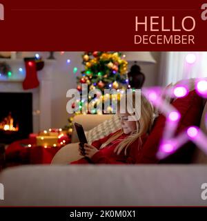 Composition of hello december text over caucasian girl using smartphone Stock Photo