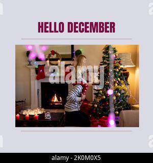 Composition of hello december text over caucasian father and daughter at christmas Stock Photo