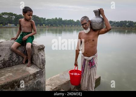 Drinking water supply and drinking water procurement from wells or freshwater ponds near Shyamnagar. The people in the small settlements along the rivers in southern Bangladesh are clearly feeling the effects of climate change. The sea level is rising and dams are being destroyed. As a result, fields and the important freshwater ponds are flooded and salinated. Therefore, great efforts are being made to fortify the banks. Residential buildings are being raised and fortified as well. Suesswater harvesting projects are very important to provide people with clean drinking water. Stock Photo