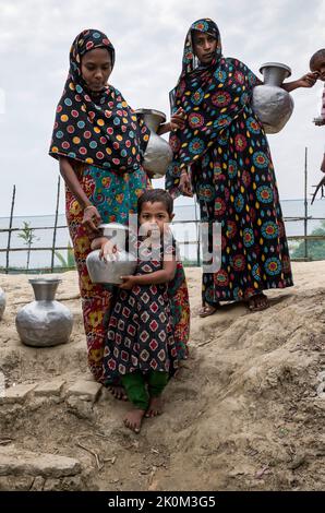 Drinking water supply and drinking water procurement from wells or freshwater ponds near Shyamnagar. The people in the small settlements along the rivers in southern Bangladesh are clearly feeling the effects of climate change. The sea level is rising and dams are being destroyed. As a result, fields and the important freshwater ponds are flooded and salinated. Therefore, great efforts are being made to fortify the banks. Residential buildings are being raised and fortified as well. Suesswater harvesting projects are very important to provide people with clean drinking water. Stock Photo