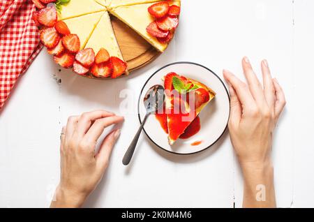 Piece of cheesecake with fresh strawberries jam and mint. Tasty homemade cheesecake on a white background. Top view Stock Photo