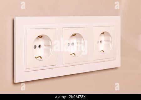 Group of white european electrical outlets on modern beige wall. Selective focus Stock Photo