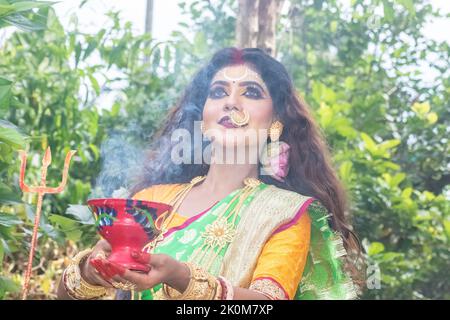 Married women performing dhunuchi dance on the occasion of Durga Agomoni as ritual ,Holy smoke covered entire area. Stock Photo