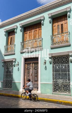 Cyclist driving in front of a colonial building, Merida Mexico Stock Photo