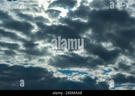 Blue sky with thunderclouds. The sun breaks through the clouds. Black clouds. Stock Photo