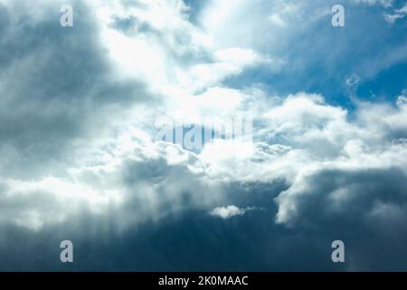 Blue sky with thunderclouds. The sun breaks through the clouds. Black clouds. Stock Photo