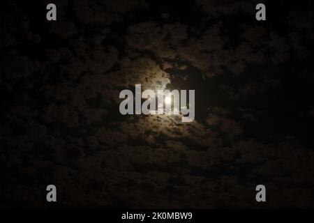 Close up night photo of full moon on cloudy sky. Stock Photo