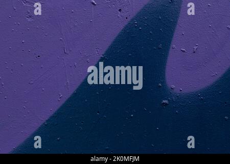 Close-up of a dark blue spray painted wall with purple wave shapes. Abstract full frame textured grunge graffiti background with copy space. Stock Photo