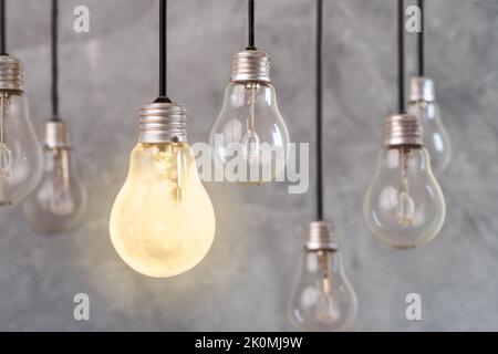 Close up photo of multiple light bulbs and one of them is shinning as a symbol of idea, creative solution or innovation. Stock Photo