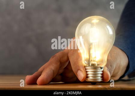 Close up photo of shining single light bulb on green blurred background. Stock Photo