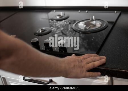 Installation of a gas three-burner built-in stove in a black countertop. Kitchen interier. Stock Photo